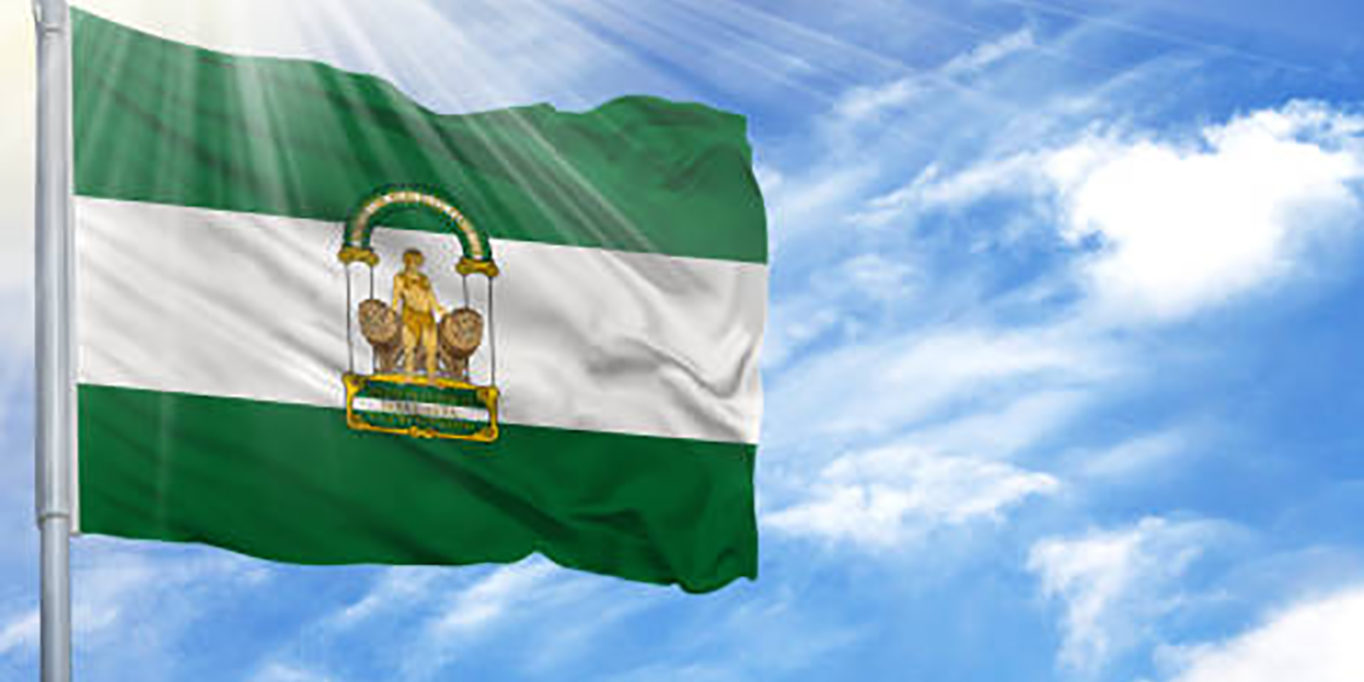 Flag of Andalusia on flagpole against the blue sky.