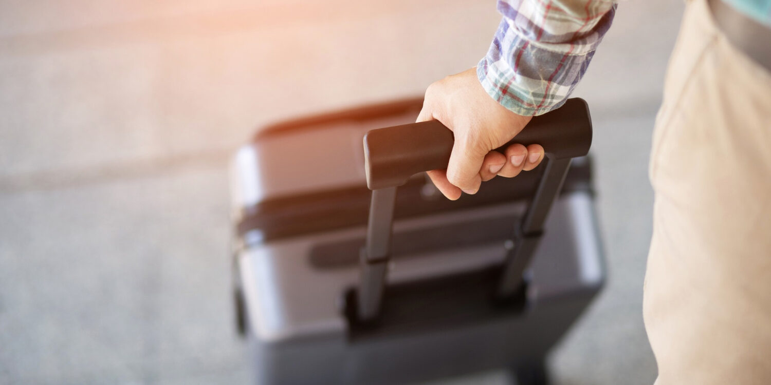 man-walking-with-luggage-traveler-pulling-suitcase-closeup-view