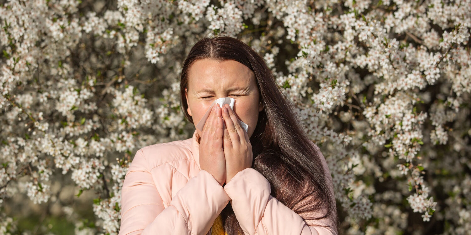 spring-allergy-symptoms-concept-young-woman-sneezing-front-blooming-tree-allergy-pollen-flowering-season-healthcare