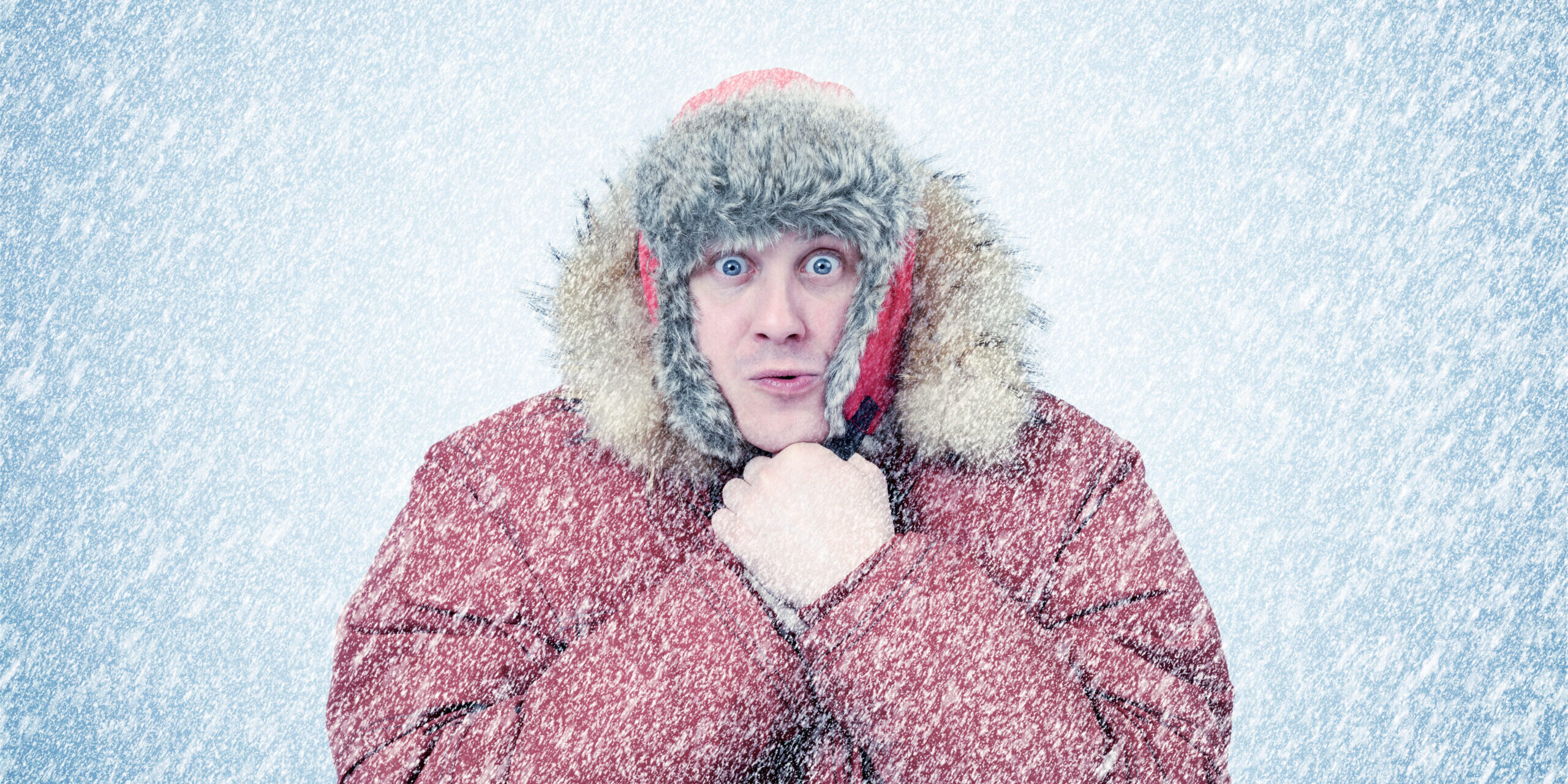 Frozen man in winter clothes warming hands, cold, snow, blizzard